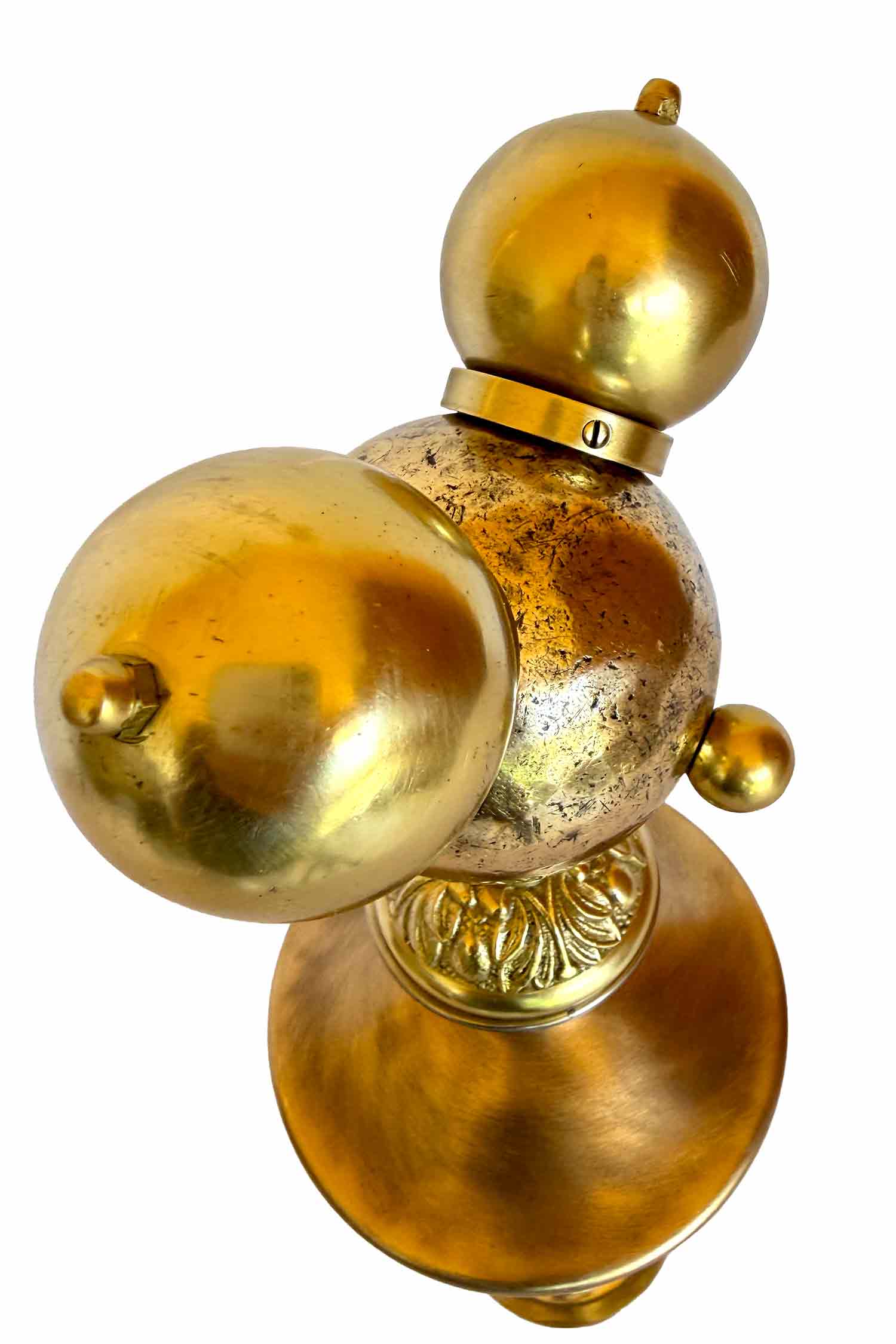 A gilded sculpture with a pétanque ball for each face and two knobs for ears; the body and legs are also gilded and are made of lampshade parts.
